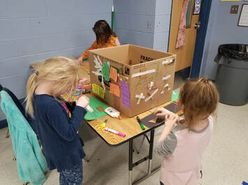 Kinder students working on a cardboard piece