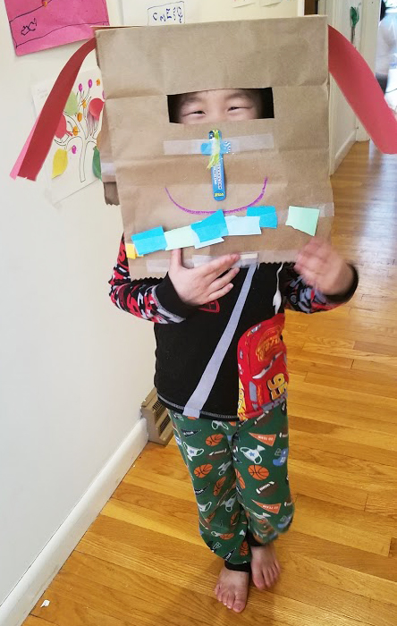 Kindergarten boy with a paper bag mask.